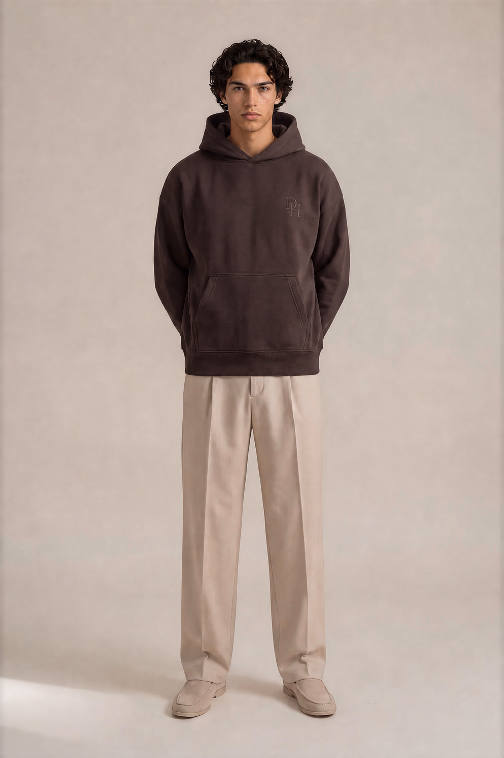 Close editorial crop of the stringless espresso Dynast Heir hoodie and tonal wearer-left chest embroidery